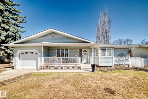 Light blue vinyl siding exterior with an attached garage, covered front porch, and a white paneled front door - 17 Springfield Crescent, St. Albert, AB - Outdoor With Deck Patio Veranda