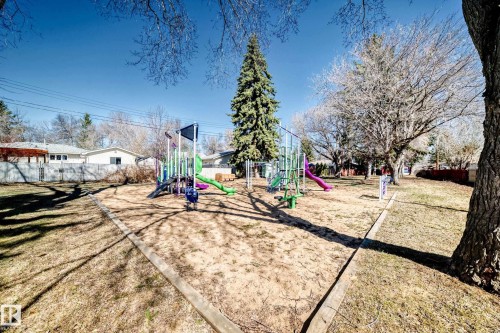 Outdoor play area featuring multi-colored play structures with slides, climbing elements, and a sand base - 17 Springfield Crescent, St. Albert, AB - Outdoor