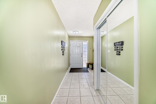 Entryway featuring light-toned square floor tiling, a frosted glass panel entry door, and a full-height mirrored closet - 17 Springfield Crescent, St. Albert, AB - Indoor Photo Showing Other Room