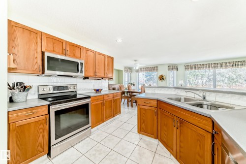 Kitchen featuring wood cabinetry, stainless steel appliances, and tile flooring - 17 Springfield Crescent, St. Albert, AB - Indoor Photo Showing Kitchen With Double Sink