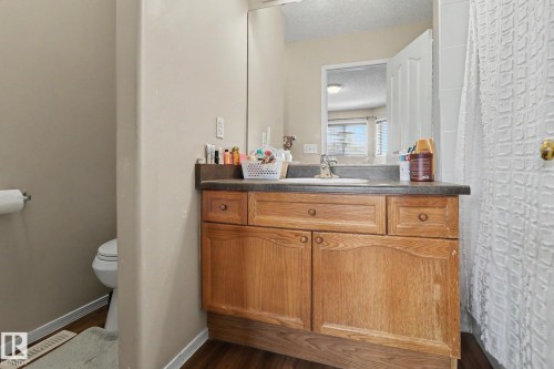 Wood-finish vanity with a single basin sink and dark countertop - 11633 167B Avenue, Edmonton, AB - Indoor Photo Showing Bathroom