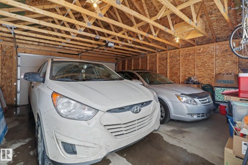 Attached two-car garage featuring a white overhead door and exposed wood framing - 11633 167B Avenue, Edmonton, AB - Indoor Photo Showing Garage