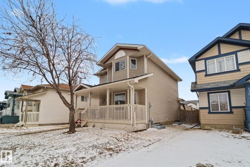 Two-story property featuring light beige siding, a covered front porch with white railings, and a peaked roofline - 11633 167B Avenue, Edmonton, AB - Outdoor With Deck Patio Veranda