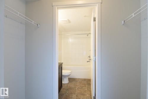 Bathroom entrance with wire shelving and a white tub-shower combination featuring subway tiling - 111 25 Element Dr, St. Albert, AB - Indoor Photo Showing Bathroom