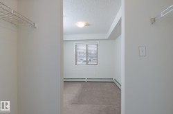 Room featuring soft neutral carpeting, a large window with horizontal blinds, and a built-in wire shelving system - 