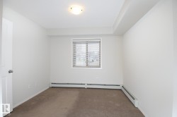 Carpeted room featuring a white door with a brushed nickel knob, a rectangular window with horizontal blinds, and two baseboard heating units - 