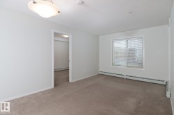 Neutral-toned carpeting extends throughout this room, complemented by a window with horizontal blinds - 