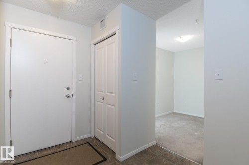Entry foyer featuring a white entrance door with brushed nickel hardware, bifold closet doors, and tile flooring - 111 25 Element Dr, St. Albert, AB - Indoor Photo Showing Other Room