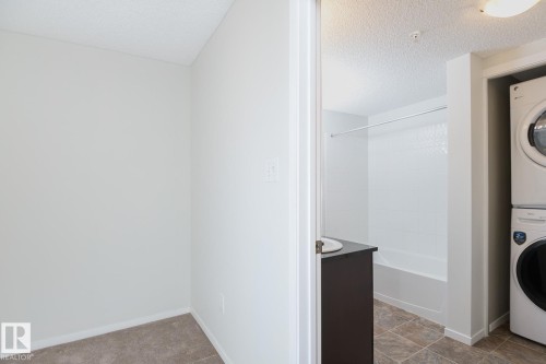 Bathroom featuring a white tub, shower with a white surround, and a dark brown vanity with a white basin sink - 111 25 Element Dr, St. Albert, AB - Indoor Photo Showing Laundry Room