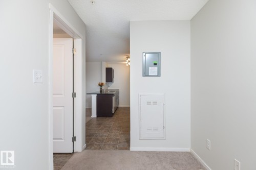 Kitchen with dark wood cabinetry, light-colored countertops, and tile flooring, visible through an open doorway - 111 25 Element Dr, St. Albert, AB - Indoor Photo Showing Other Room