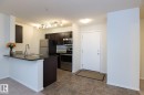 Kitchen and entryway featuring dark wood-finish cabinetry, stainless steel appliances, a breakfast bar with a dark countertop, and tiled flooring - 111 25 Element Dr, St. Albert, AB  - Indoor Photo Showing Kitchen 