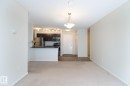 Open-concept living space with light-colored carpeting, a kitchen featuring dark wood cabinetry, stainless steel appliances, and a black countertop - 111 25 Element Dr, St. Albert, AB  - Indoor Photo Showing Kitchen 