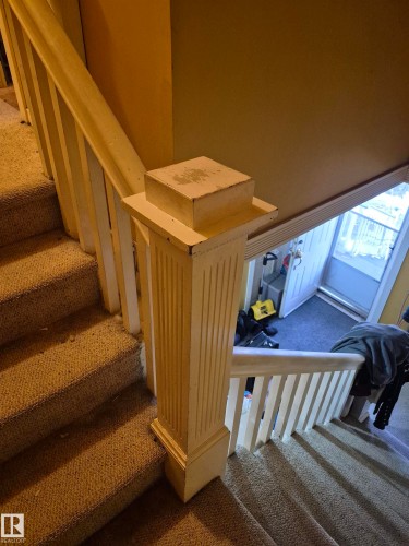 Carpeted staircase featuring a substantial fluted newel post and painted wooden balustrade - 11301 87 Street, Edmonton, AB - Indoor Photo Showing Other Room