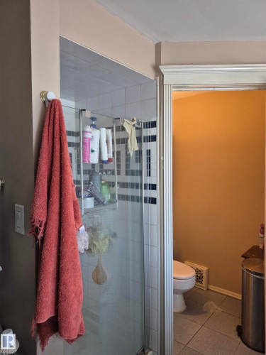 Primary bathroom with glass-enclosed shower with white tiled walls and a decorative black and white accent band - 11301 87 Street, Edmonton, AB - Indoor Photo Showing Bathroom