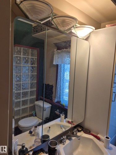 Bathroom vanity featuring a medicine cabinet with mirrored doors, an integrated sink, and dual-handle chrome faucets - 11301 87 Street, Edmonton, AB - Indoor Photo Showing Bathroom