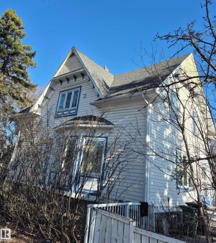 Two-story exterior featuring light-colored siding, a prominent gable roof with decorative shingles, and a bay window - 11301 87 Street, Edmonton, AB - Outdoor
