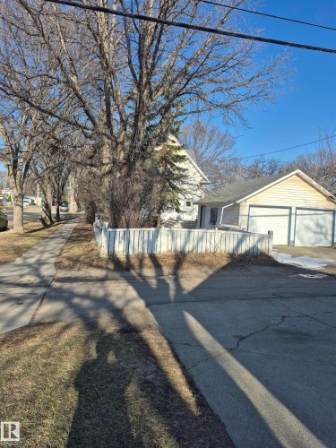 Two-car garage with white paneled doors and blue trim, visible from a paved driveway - 11301 87 Street, Edmonton, AB - Outdoor
