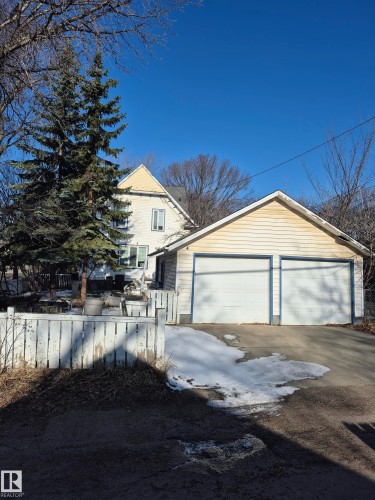 Detached two-car garage with white paneled doors and a light-colored siding exterior, featuring a visible pitched roofline - 11301 87 Street, Edmonton, AB - Outdoor
