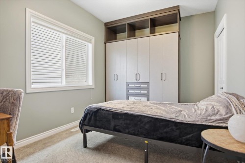 Built-in wardrobe system with contrasting wood-finish shelving and light-toned cabinet doors featuring modern pulls - 28 Hewitt Circle, Spruce Grove, AB - Indoor Photo Showing Bedroom