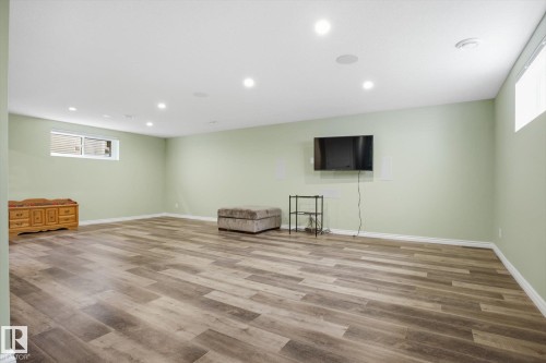 Spacious room featuring wood-finish flooring, recessed lighting, light green walls, and white trim - 28 Hewitt Circle, Spruce Grove, AB - Indoor
