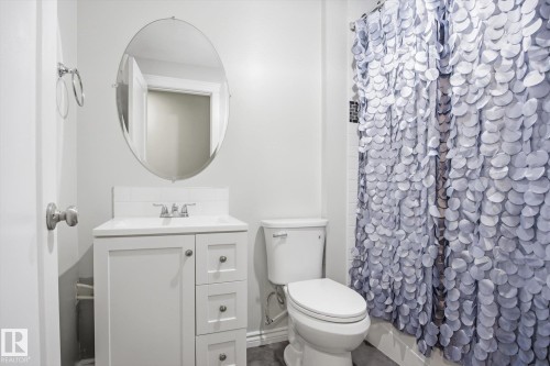 Bathroom featuring a white vanity with integrated sink, chrome faucet, and an oval mirror - 28 Hewitt Circle, Spruce Grove, AB - Indoor Photo Showing Bathroom