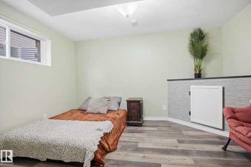 Room featuring wood-finish flooring, a neutral wall color, and a textured accent wall - 28 Hewitt Circle, Spruce Grove, AB - Indoor Photo Showing Bedroom