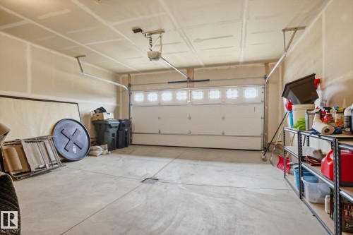 Spacious attached garage featuring a white overhead door with upper window inserts, concrete flooring, and an automatic garage door opener - 28 Hewitt Circle, Spruce Grove, AB - Indoor Photo Showing Garage