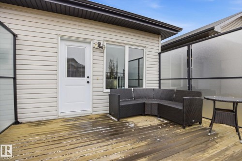 Spacious wood-finish deck with privacy screens featuring a white exterior door, two windows, and exterior lighting - 28 Hewitt Circle, Spruce Grove, AB - Outdoor With Exterior