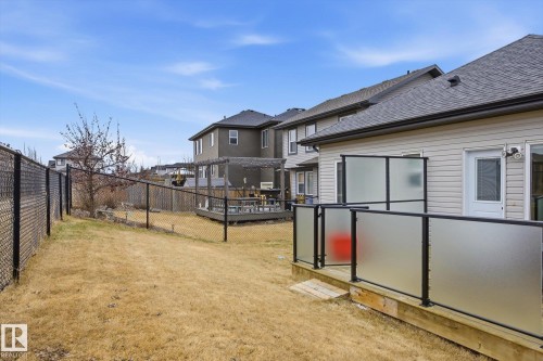 Private outdoor space featuring a wood deck with frosted glass panel railing, vinyl siding, and chain-link fencing - 28 Hewitt Circle, Spruce Grove, AB - Outdoor
