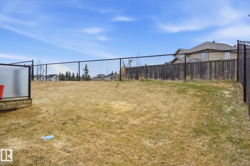 Expansive sloped yard featuring a chain-link fence, wood privacy fence, and a partial deck with frosted panels - 28 Hewitt Circle, Spruce Grove, AB - Outdoor