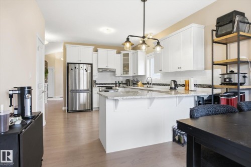 Kitchen featuring white cabinetry, stainless steel appliances, a center island with a light-colored countertop, and a tiled backsplash - 28 Hewitt Circle, Spruce Grove, AB - Indoor Photo Showing Kitchen With Stainless Steel Kitchen With Upgraded Kitchen
