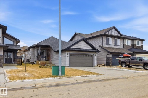 Contemporary home featuring grey siding, dark shingle roofing, an attached double garage, and a covered front porch with stone accents - 28 Hewitt Circle, Spruce Grove, AB - Outdoor With Facade