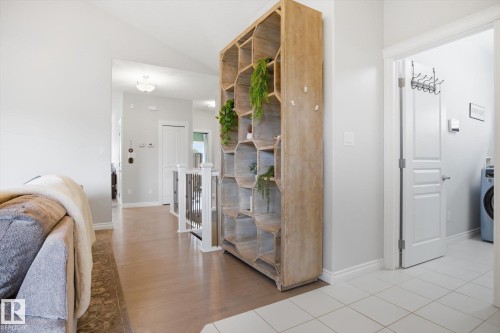 Expansive hallway featuring wood-finish flooring, a contemporary honeycomb-patterned shelving unit, white baseboards, and a white ceiling with recessed lighting - 28 Hewitt Circle, Spruce Grove, AB - Indoor