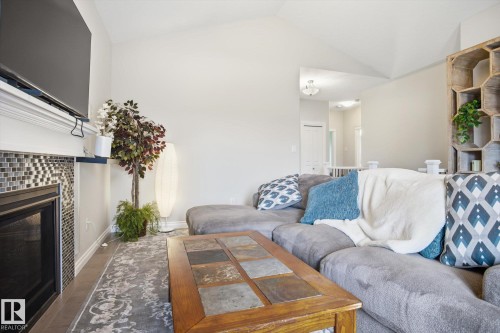 Living area featuring vaulted ceilings, a built-in fireplace with mosaic tile surround, and a white mantel - 28 Hewitt Circle, Spruce Grove, AB - Indoor Photo Showing Living Room With Fireplace