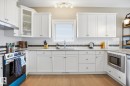 Contemporary kitchen featuring white cabinetry, light-toned wood-finish flooring, a stainless steel range, and a built-in microwave - 28 Hewitt Circle, Spruce Grove, AB  - Indoor Photo Showing Kitchen With Double Sink 