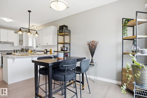 Modern kitchen featuring white cabinetry, a granite island countertop, a tiled backsplash, and wood-finish flooring - 28 Hewitt Circle, Spruce Grove, AB - Indoor