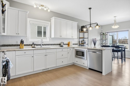 Modern kitchen featuring white cabinetry, light-colored countertops, and wood-finish flooring - 28 Hewitt Circle, Spruce Grove, AB - Indoor Photo Showing Kitchen