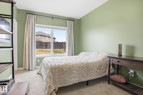 Bedroom featuring a large picture window with white trim, light green painted walls, and neutral-toned carpeting - 28 Hewitt Circle, Spruce Grove, AB - Indoor Photo Showing Bedroom