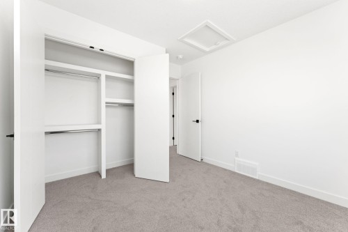 Bedroom featuring light gray carpeting, crisp white walls, and a built-in closet with shelving and hanging rods - 94 Blackbird Bend, Fort Saskatchewan, AB - Indoor Photo Showing Other Room