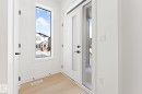 The entryway features light hardwood flooring, white walls, and a modern white door with a frosted glass panel - 94 Blackbird Bend, Fort Saskatchewan, AB  - Indoor Photo Showing Other Room 