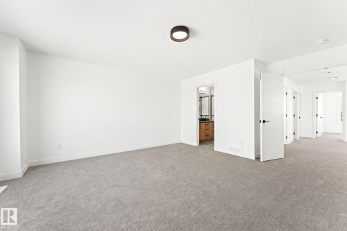 This spacious interior features light grey carpeting and crisp white walls, creating a neutral canvas - 94 Blackbird Bend, Fort Saskatchewan, AB - Indoor Photo Showing Other Room