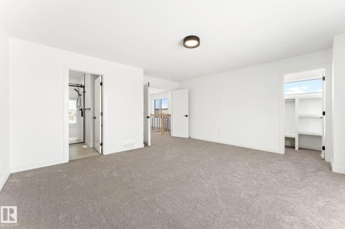 Spacious room featuring light gray carpeting, crisp white walls, and a contemporary ceiling light fixture - 94 Blackbird Bend, Fort Saskatchewan, AB - Indoor Photo Showing Other Room