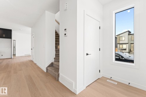 Well-lit entryway featuring light hardwood floors, a white door with dark hardware, and a window providing natural light - 94 Blackbird Bend, Fort Saskatchewan, AB - Indoor Photo Showing Other Room