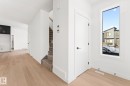 Well-lit entryway featuring light hardwood floors, a white door with dark hardware, and a window providing natural light - 94 Blackbird Bend, Fort Saskatchewan, AB  - Indoor Photo Showing Other Room 