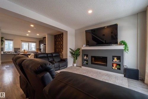 Living area featuring a contemporary fireplace with integrated shelving, recessed lighting, and wood-finish flooring - 117 804 Welsh Drive, Edmonton, AB - Indoor Photo Showing Living Room With Fireplace