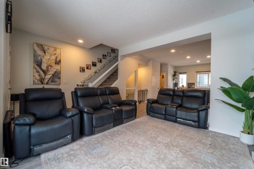 Open-concept living space featuring wood-finish flooring, a neutral color palette, recessed lighting, and a staircase with carpeted treads - 117 804 Welsh Drive, Edmonton, AB - Indoor Photo Showing Living Room