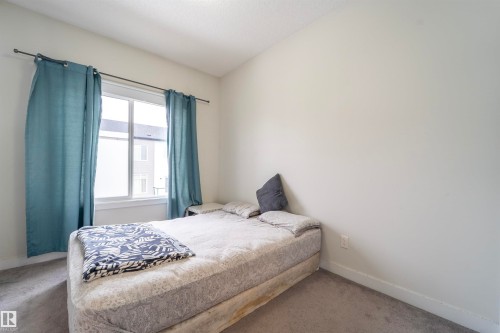 Carpeted room featuring a large window with white trim, light-colored walls, and white baseboards - 117 804 Welsh Drive, Edmonton, AB - Indoor Photo Showing Bedroom