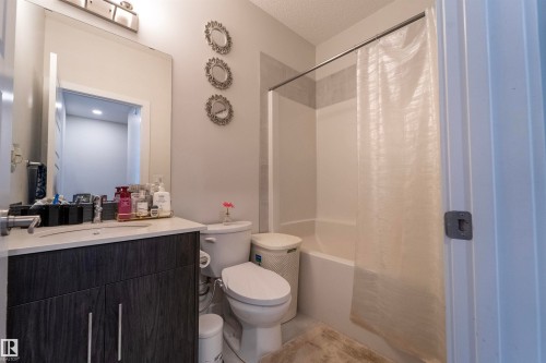 Bathroom featuring a dark wood-finish vanity with an integrated sink, a white countertop, and a chrome faucet - 117 804 Welsh Drive, Edmonton, AB - Indoor Photo Showing Bathroom
