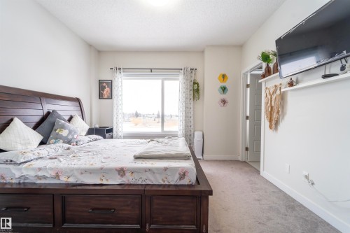 Spacious room featuring a large window, light-toned walls, and soft carpet flooring - 117 804 Welsh Drive, Edmonton, AB - Indoor Photo Showing Bedroom