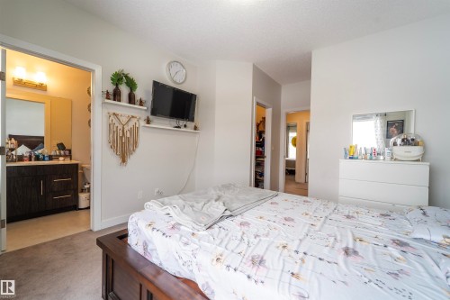 Carpeted bedroom featuring a wooden bed frame and light-toned walls - 117 804 Welsh Drive, Edmonton, AB - Indoor Photo Showing Bedroom